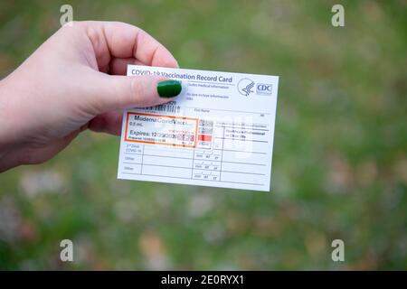 Femme tenant une carte de vaccin Covid 19 Moderna pour preuve De la première dose délivrée par le CDC USA Government Banque D'Images