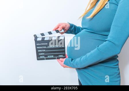 Femme enceinte hands holding clapper board sur son ventre Banque D'Images