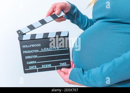 Femme enceinte hands holding clapper board sur son ventre Banque D'Images