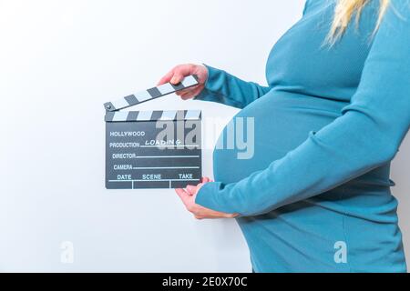 Femme enceinte hands holding clapper board sur son ventre Banque D'Images