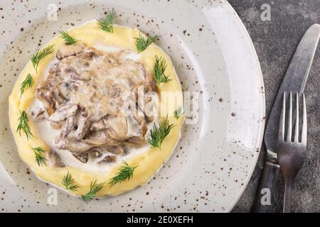 Bœuf avec purée de pommes de terre dans une assiette blanche avec couverts. Photo pour le menu. Banque D'Images