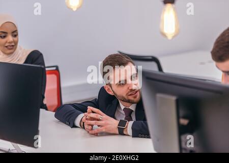 Jeune homme beau ayant une conversation d'affaires avec ses collègues. Banque D'Images