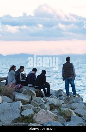 Groupe de jeunes amis proches qui regardent le coucher du soleil à White Rock, en Colombie-Britannique Banque D'Images