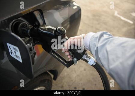 Dylan Stewart pompe du gaz tout en utilisant un gant en caoutchouc pour protéger du nouveau coronavirus, le lundi 28 décembre 2020 à Barstow, en Californie (Dylan Stewart/Imag Banque D'Images