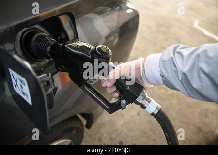 Dylan Stewart pompe du gaz tout en utilisant un gant en caoutchouc pour protéger du nouveau coronavirus, le lundi 28 décembre 2020 à Barstow, en Californie (Dylan Stewart/Imag Banque D'Images