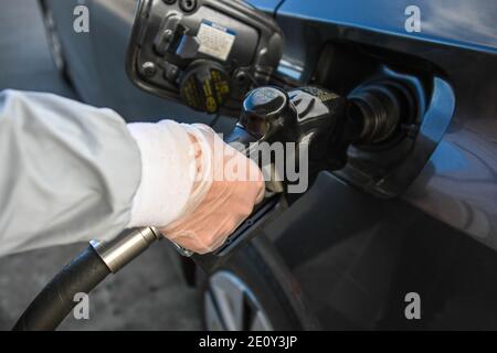 Dylan Stewart pompe du gaz tout en utilisant un gant en caoutchouc pour protéger du nouveau coronavirus, le lundi 28 décembre 2020 à Barstow, en Californie (Dylan Stewart/Imag Banque D'Images