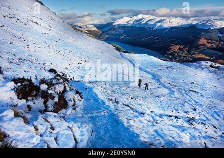 Les marcheurs sur les collines montent à Ben Ledi, près de Callander vu avec la neige d'hiver en janvier 202. Le Loch Lubnaig est vu au loin. Banque D'Images