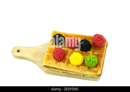 Bonbons en gelée de différentes couleurs et délicieuses gaufres belges sur un fond blanc isolé. Gaufres sucrées avec morceaux de chocolat et candi coloré Banque D'Images