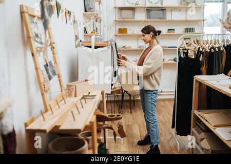 Femme curieuse dans un magasin écologique à la recherche de tissu ECO sacs sur un rack Banque D'Images