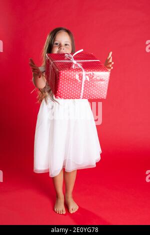 belle fille pleine longueur dans une robe blanche et pieds nus jette un coffret cadeau dans l'air, isolé sur un fond de vibration Banque D'Images