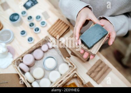 Mains de femme tenant un savon écologique et un porte-savon en bois. Vue de dessus Banque D'Images