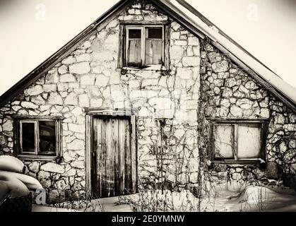 Ancienne maison en pierre abandonnée sur une vieille photo en noir et blanc. Banque D'Images