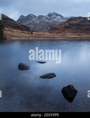 Magnifique lever de soleil d'hiver sur Blea Tarn dans Lake District avec Au loin, Langdale Pikes a été enneigé Banque D'Images