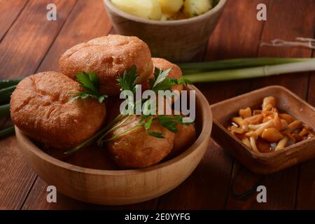 Pains farcis (Pirozhki) dans un bol en bois sur fond de bois. Avec des oignons verts et des champignons agariques au miel marinés faits maison, et des pommes de terre. Fait maison Banque D'Images