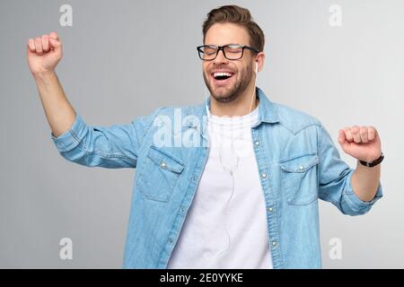 Portrait en gros plan d'un jeune homme joyeux qui apprécie l'écoute musique portant un ensemble jean décontracté Banque D'Images