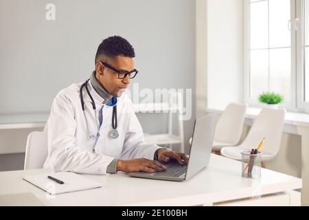 Médecin utilisant un ordinateur portable pour donner la consultation en ligne ou pour remplir dans les dossiers médicaux électroniques Banque D'Images