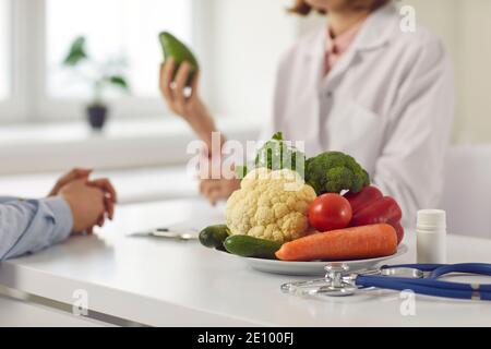 Gros plan d'une assiette avec des légumes sur le fond d'un nutritionniste qui fournit la consultation. Banque D'Images