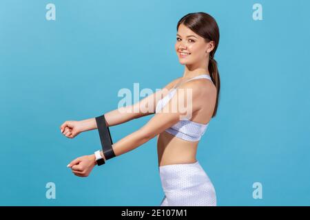 Portrait de profil sourire la femme athlète de persistance tient la bande expansible de caoutchouc sur les mains, en utilisant la corde élastique pour l'étirement de muscle et de travail de force Banque D'Images
