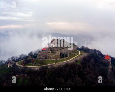 Les ruines du château de la citadelle de Visegrad dans la courbe du Danube en Hongrie. Paysage aérien fantastique par mauvais temps. Lever de soleil brumeux et nuageux Banque D'Images