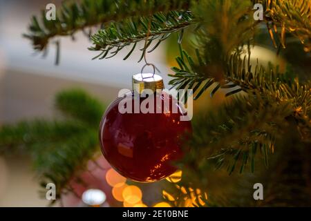Fond de Noël festif avec boule rouge colorée et bokeh de lumières dorées étincelantes décorant un arbre traditionnel pendant le saison des fêtes Banque D'Images