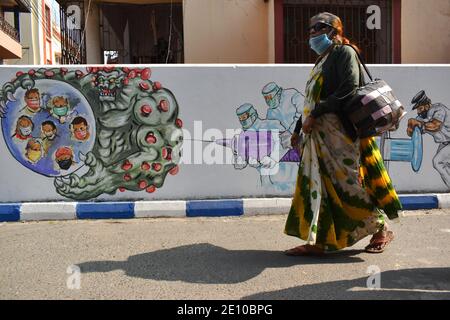 Une femme passe devant un graffiti mural qui parle des guerriers du front et de la vaccination à Kolkata. L'Inde a ajouté 18,177 cas d'infection à coronavirus au cours des 24 dernières heures, ce qui a placé son nombre global à 1.03 cas de coronavirus. Le régulateur indien des médicaments a approuvé dimanche le vaccin Oxford COVID-19 Covishield, fabriqué par le Serum Institute, et a développé de manière indivisible Covaxin de Bharat Biotech pour une utilisation d'urgence restreinte dans le pays, ouvrant la voie à une importante campagne d'inoculation. (Photo de Sudipta Das/Pacific Press) Banque D'Images