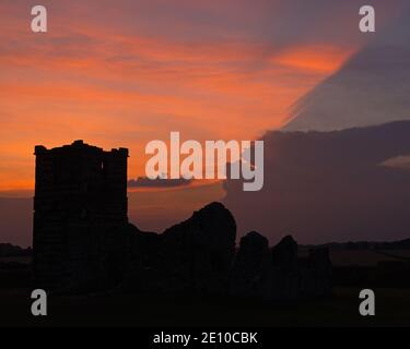 Une photo au coucher du soleil de l'église Knowlton à Dorset, Angleterre, Royaume-Uni, par une journée partiellement nuageux avec la lumière du soleil créant un éclairage intéressant des nuages. Banque D'Images