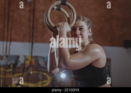 Photo basse d'une athlète féminine gaie crossfit reposant après avoir fait de l'entraînement sur des anneaux de gymnastique, espace de copie Banque D'Images