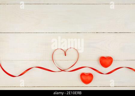 Composition romantique créative de la Saint-Valentin avec coeurs rouges, ruban en satin sur fond de bois. Maquette avec espace de copie pour blogs et réseaux sociaux Banque D'Images