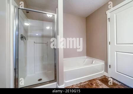 Cabine de douche et baignoire à l'intérieur d'une salle de bains propre avec brun carreaux sur le sol Banque D'Images