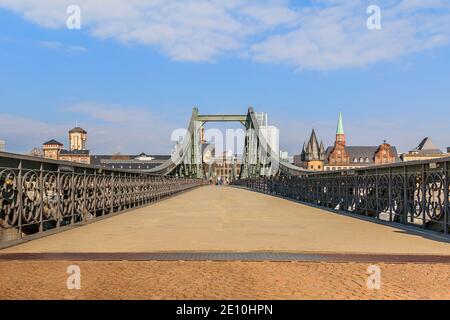 Passerelle historique sur le main à Francfort. Pont de fer pendant la journée avec peu de personnes. Maisons de la vieille ville en arrière-plan avec soleil Banque D'Images