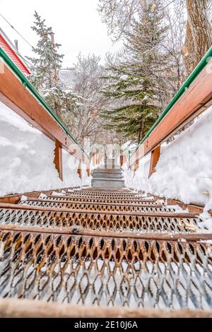 Escalier de montagne extérieur avec bandes métalliques et mains courantes contre la neige et les arbres Banque D'Images