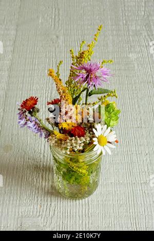 Arrangement de fleurs sauvages sur un dessus de table en bois blanc cassé 1 Banque D'Images