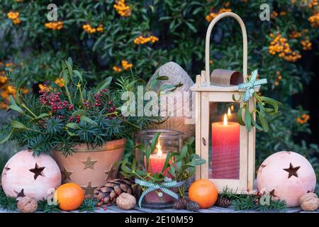 décoration de noël rustique avec lanterne et bouquet de branches de ragoût, gui et hanches roses Banque D'Images