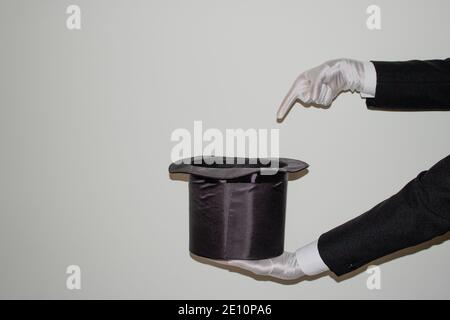Portrait du jeune magicien noir de l'Ilusionniste faisant de la magie avec un chapeau et baguette magique isolés sur un blanc arrière-plan Banque D'Images
