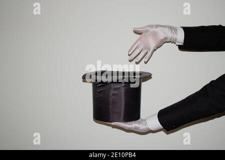 Portrait du jeune magicien noir de l'Ilusionniste faisant de la magie avec un chapeau et baguette magique isolés sur un blanc arrière-plan Banque D'Images