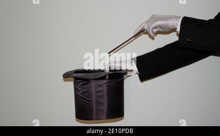 Portrait du jeune magicien noir de l'Ilusionniste faisant de la magie avec un chapeau et baguette magique isolés sur un blanc arrière-plan Banque D'Images