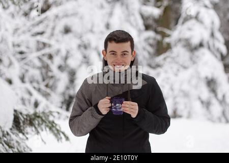 Hiver - Homme dans la neige, réchauffant avec une boisson chaude. Contenant une tasse de thé ou de vin chaud. Banque D'Images