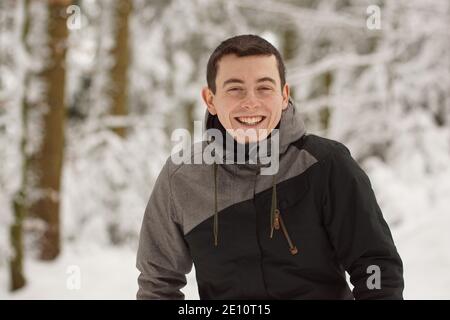 Hiver - un jeune homme heureux s'amusant dans la neige et riant, souriant dans l'appareil photo Banque D'Images