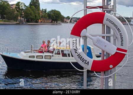 Stockholm, Suède - 12 juillet 2020 : sécurité maritime suédoise avec bouée de sauvetage en premier plan et personnes sur un bateau en arrière-plan Banque D'Images