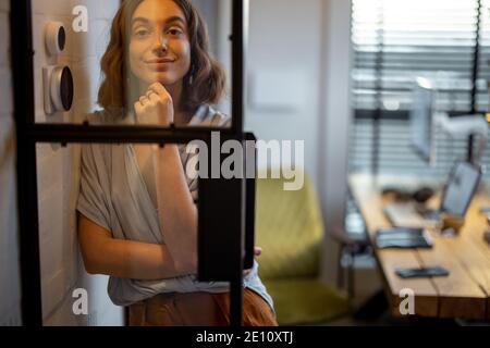 Portrait d'une jeune femme gaie debout à l'agréable et un bureau à domicile élégant Banque D'Images