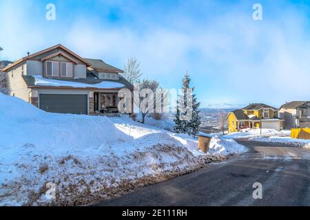 Quartier enneigé avec maisons et route donnant sur la vallée et la montagne vues Banque D'Images
