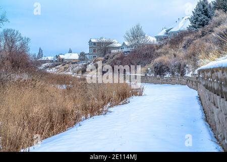 Maisons surplombant le sentier enneigé le long de la côte de l'Utah Lac sous ciel nuageux Banque D'Images