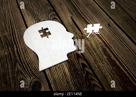Puzzle manquant de la tête humaine construire à partir de pièces de puzzle sur des planches de bois, avec une pièce brillante courir plus près de lui. illustration 3d Banque D'Images