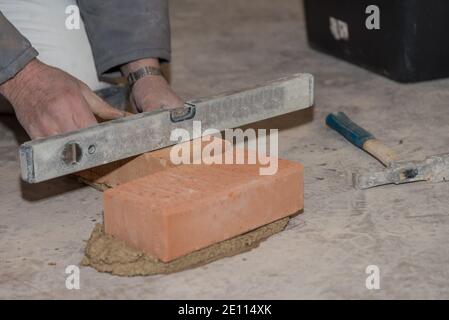 Mason construit le mur de briques et mesure avec le niveau Esprit - Gros plan Banque D'Images