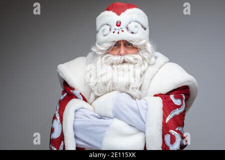 Le Père Noël sérieux a croisé ses bras sur sa poitrine et insatisfait, portrait de studio sur fond gris Banque D'Images