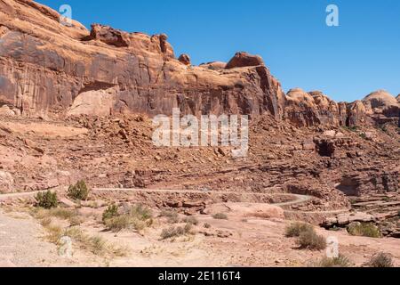 Un camion qui descend sur Kane Creek Road à travers d'imposantes roches de grès rouge, Moab, Utah, États-Unis Banque D'Images