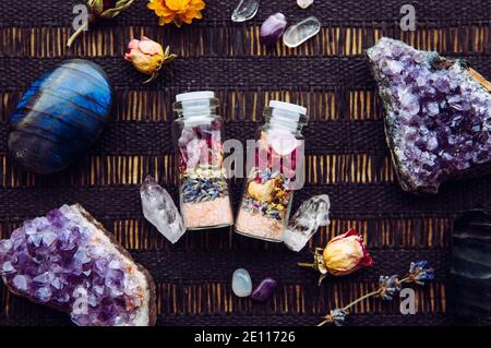 Flacons en pot à la main avec de bonnes intentions pour la protection de la maison et l'équilibre intérieur. Rempli de sel de roche himalayan, de fleurs d'herbes séchées. Banque D'Images