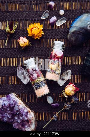 Flacons en pot à la main avec de bonnes intentions pour la protection de la maison et l'équilibre intérieur. Rempli de sel de roche himalayan, de fleurs d'herbes séchées. Banque D'Images