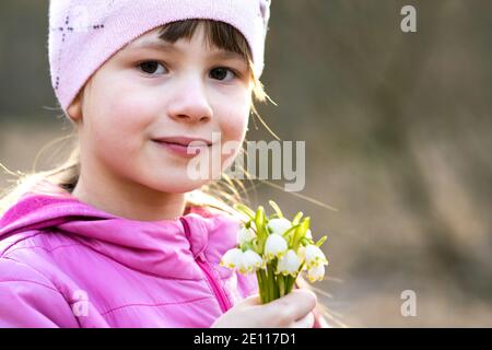 Portrait d'une jeune fille heureuse tenant un bouquet de fleurs de neige printanière plein air. Banque D'Images