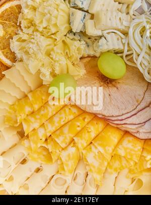Vue de dessus différents types de fromage avec des tranches d'orange séchées, des tranches de pomme séchées, et des raisins en gros plan Banque D'Images